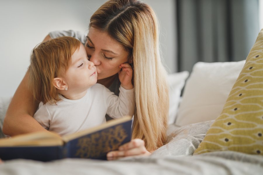 Mère et jeune enfant blottis avec un livre, un moment calme pour parler des émotions
