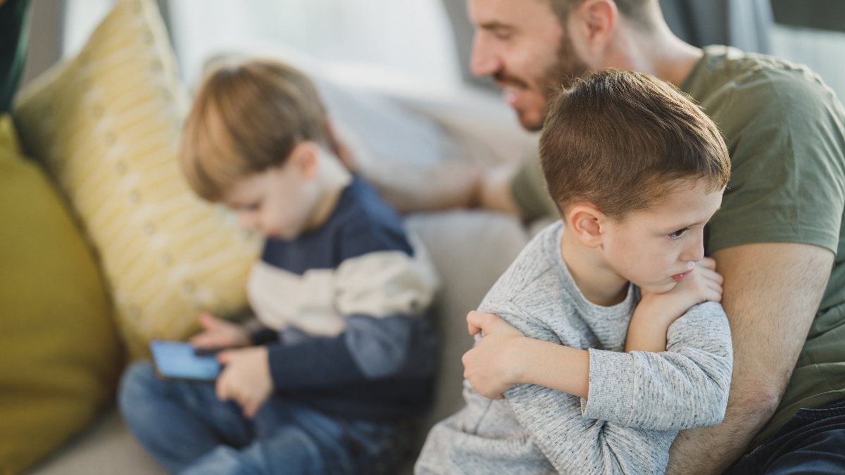 Père qui réconforte son fils contrarié sur le canapé : aider un enfant à gérer ses émotions