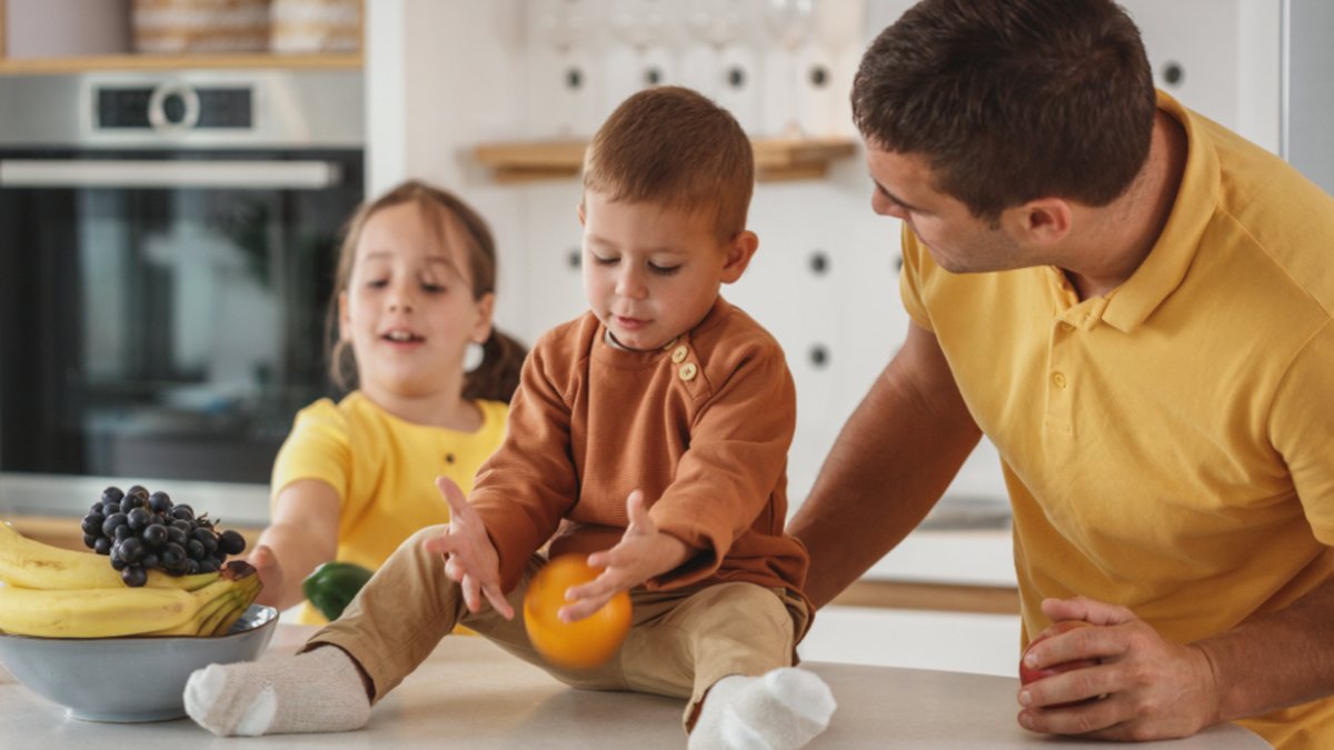 Père qui parle à hauteur de ses enfants dans la cuisine : donner une consigne à un enfant TDAH qui n'écoute pas