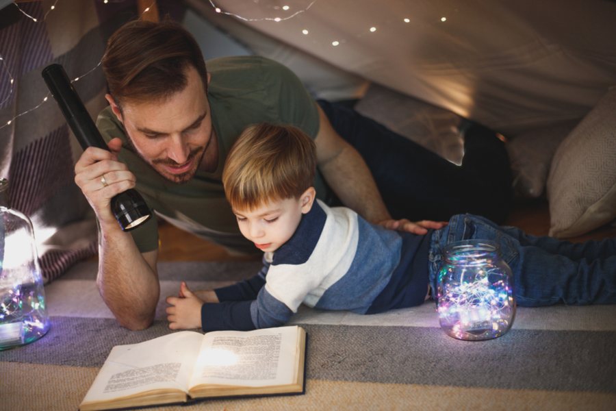 Père et fils qui lisent ensemble à la lampe de poche : soutenir un enfant dys à la maison