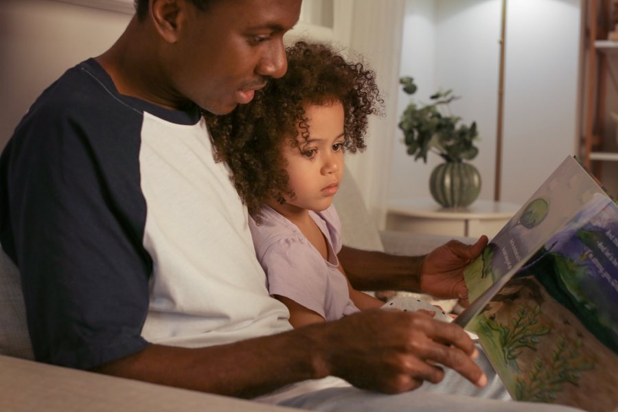 Père et fille lisant un livre illustré dans le salon : appliquer le guide HAS autisme au quotidien