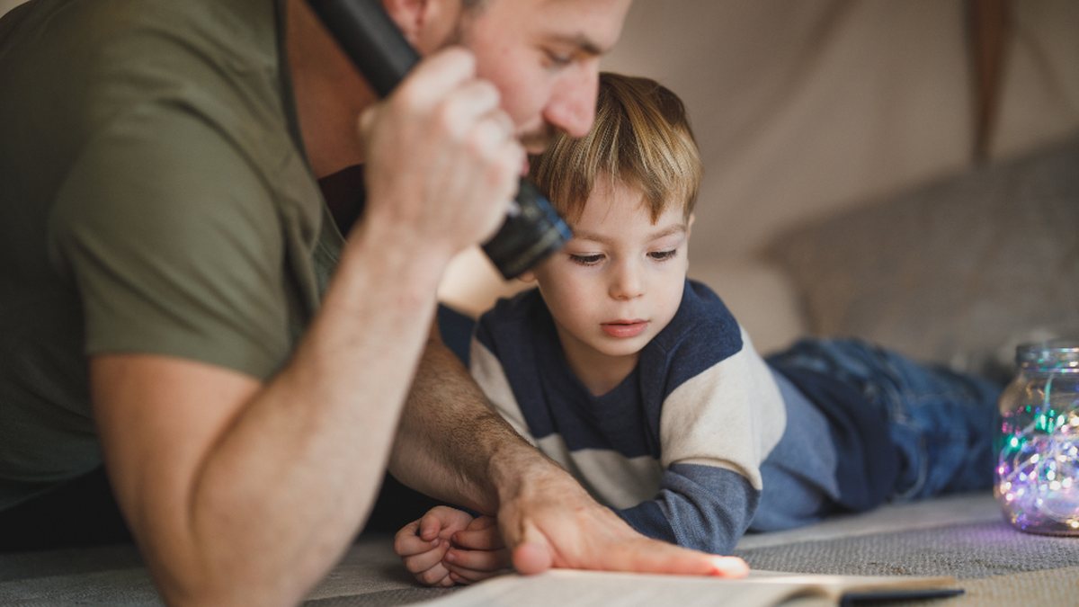 Père et fils plongés dans un livre : comprendre l'enfant à la fois HPI et TDAH
