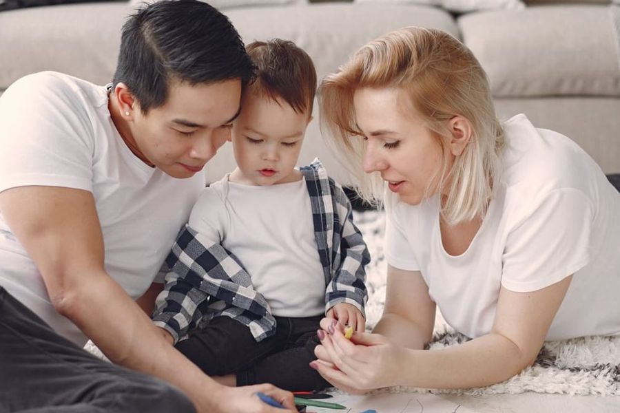 Parents et enfant assis par terre, concentrés ensemble : construire le contrat de comportement à trois