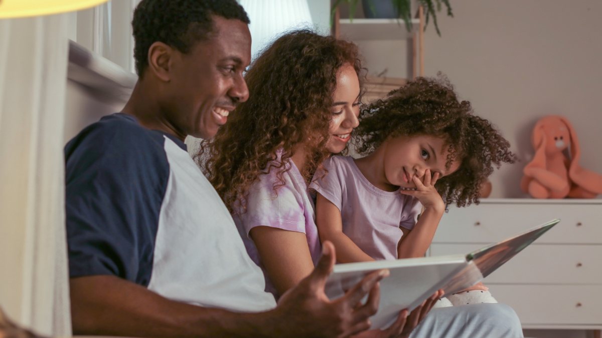 Parents et fille qui regardent un livre ensemble, prêts à construire un contrat de comportement TDAH