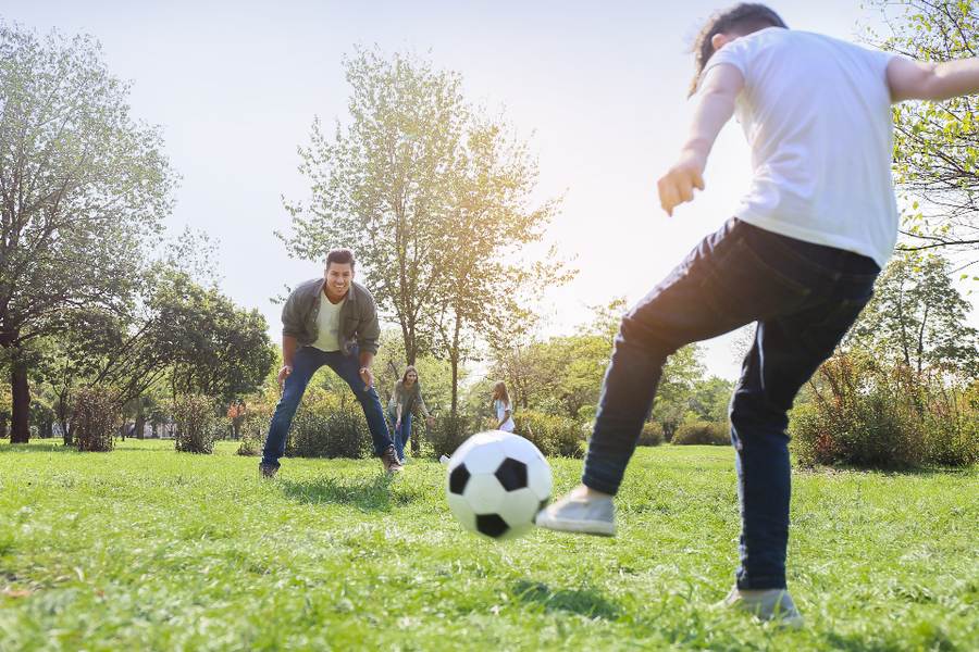 Père et fils qui jouent au ballon au parc pendant les vacances, une sortie préparée pour un enfant TDAH