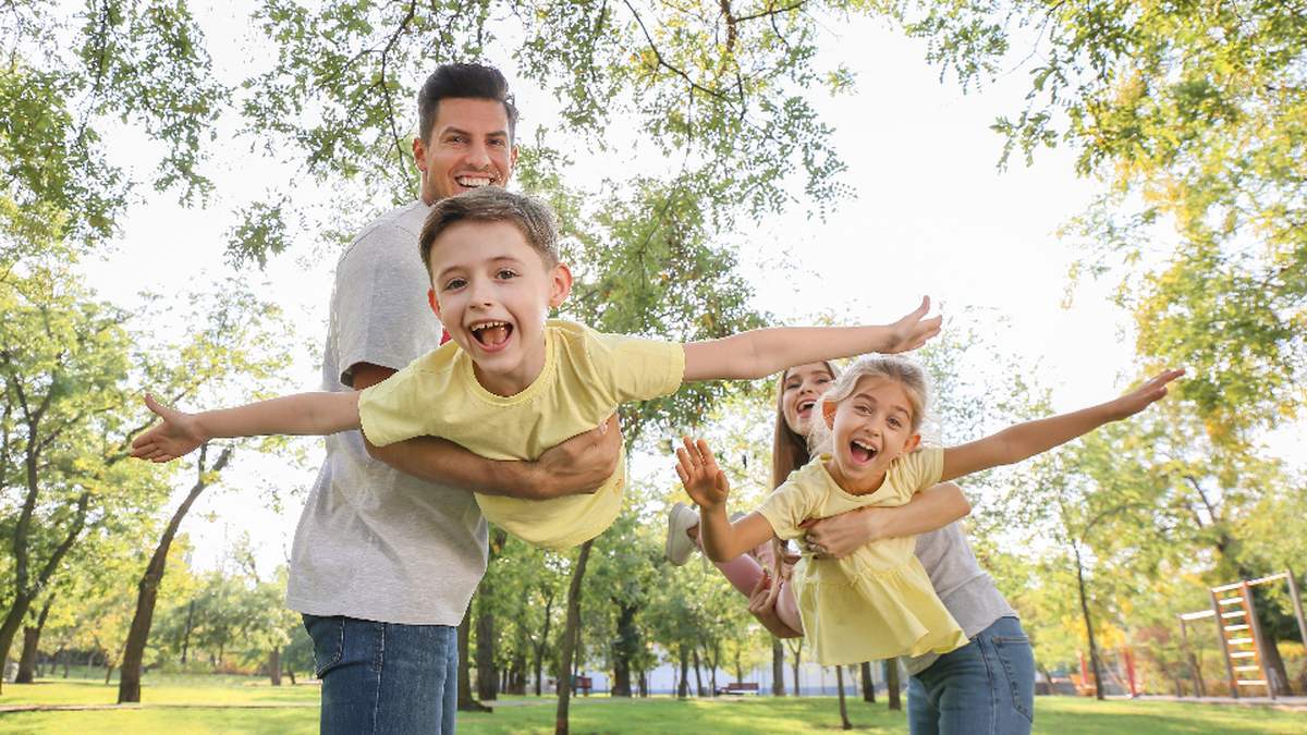Enfants qui jouent au parc avec leurs parents pendant les vacances : garder des repères pour un enfant TDAH