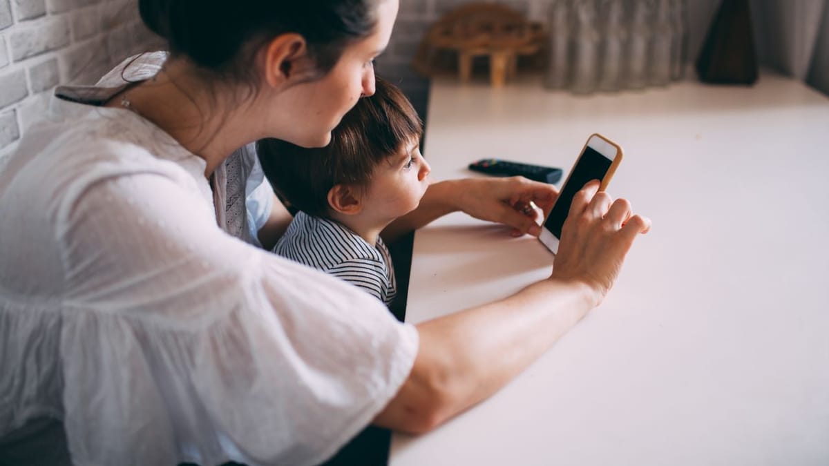 Parent et enfant utilisant une application sur téléphone ensemble
